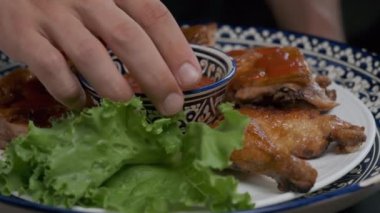 Aşçı ağır çekimde servis edilen ızgara tavuğun üzerine sos döker.