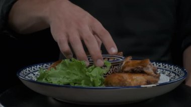 Aşçı ağır çekimde servis edilen ızgara tavuğun üzerine sos döker.