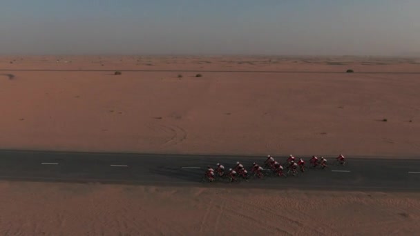 ドバイ砂漠の道路上の自転車レース ドローンカムはレーサーに続きます — ストック動画