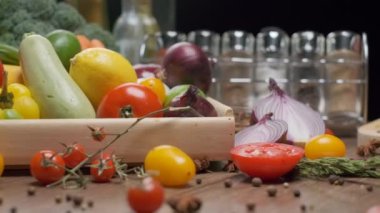 Mutfak masasında taze sebze ve baharat kavanozları var. Önünde kırmızı soğan doğranmış. Yavaş çekim