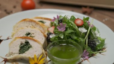 Yeşillik, çiçek süslemeleri ve yeşil yağlı bir tabakta güzelce servis edilen ıspanaklı tavuk dürümü.