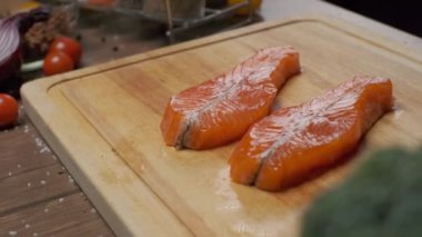 Kesme tahtasının üzerinde iki dilim somon balığı var. Ağır çekimde kapat