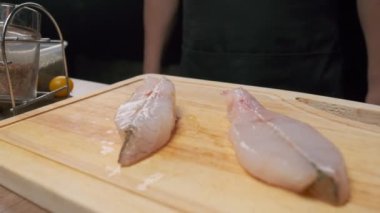 Profesyonel şef kızartılması için beyaz balık bifteği hazırlıyor. Ağır çekimde kapat.