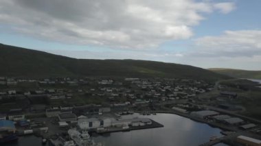 Faroe Adaları 'ndaki kıyı şeridinde kulübeler ve gemi rıhtımları. İnsansız hava aracı uçuyor