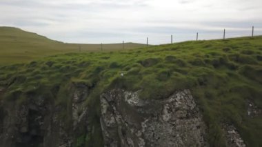 Bulutlu havada Faroe adalarının yeşil uçurumları. Drone hava görüntüsü.