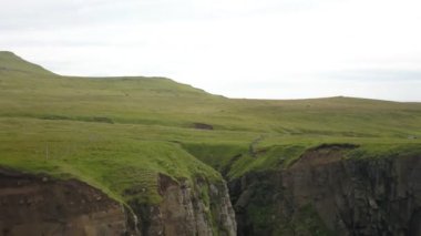 Bulutlu havada Faroe adalarının yeşil uçurumları. Drone hava görüntüsü.