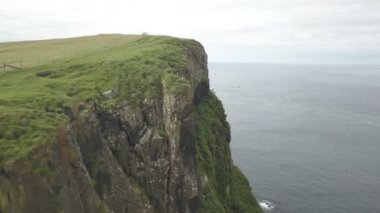 Bulutlu havada Faroe adalarının yeşil uçurumları. Drone hava görüntüsü.