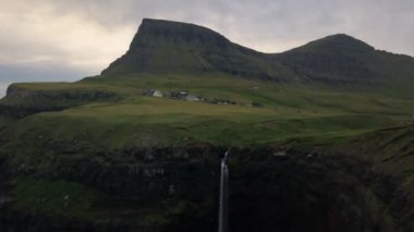 Faroe Adaları 'nın yeşil uçurumlarından denize küçük şelale düşüyor. İnsansız hava aracı.