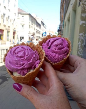 Şehir manzarasının arka planına karşı kadın elinde pembe dondurma