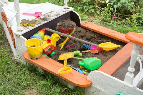 散乱の明るいおもちゃでボートの形で子供の砂場 — ストック写真