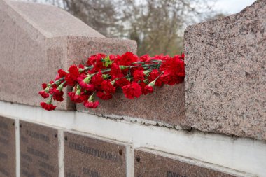 Krasnoyarsk, Rf - Mayıs 9,2018: Kırmızı karanfiller bir granit mezar taşıma düşmüş asker Zafer Anıtı adları ile Zafer Bayramı kutlama Krasnoyarsk İkinci Dünya Savaşı şehrin sırasında yalan