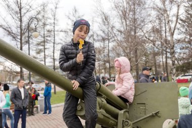 Krasnoyarsk, Rf - 9 Mayıs 2018: Oğlan hangi zafer Memorial museum yanında zafer gün ikinci Dünya Savaşı kutlamaları sırasında stand uçaksavar topçu silahı üzerinde oturuyor. Krasnoyarsk. Krasnoyarsk Bölgesi. Rusya.