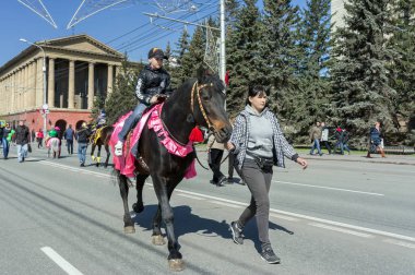 Krasnoyarsk, Rf - 9 Mayıs 2013: Çocuk zafer gün ikinci Dünya Savaşı kutlamaları sırasında Krasnoyarsk şehir cadde boyunca bir kız tarafından yönlendirilen akıllı kahverengi ata biniyor. Krasnoyarsk Bölgesi. Rusya.
