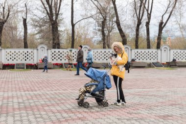 Krasnoyarsk, Rf - 9 Mayıs 2018: Bir kadın bir çocuk arabası ile a evde beslenen hayvan onun elinde tutan ve Krasnoyarsk zafer anıt, anıtları arasında bir cep telefonu bakarak yürüyor. Krasnoyarsk Bölgesi. Rusya.