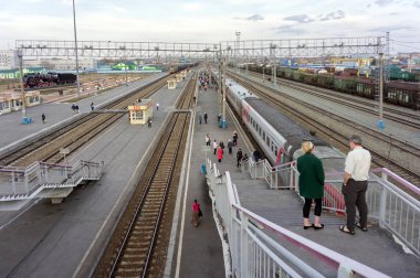 Barabinsk / Novosibirsk bölgesi / Rf - 21 Nisan 2015: demiryolu-overroad Köprüsü'nden görünümüne Barabinsk Sibirya şehir tren istasyonu platformu ile bir tren ve yürüyen yolcu,.