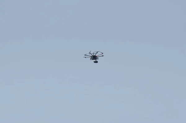 An unmanned aerial vehicle - a quad copter with a camera and a video broadcast flies across the blue sky.