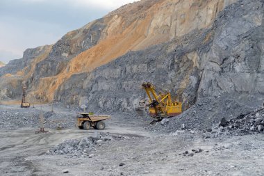 Dump truck Caterpillar loaded with nepheline ore pulls away from the excavator. The quarry operation is located in the village of Belogorsk. clipart