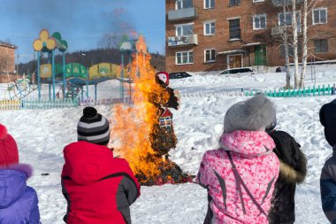 Belogorsk, Kemerovo bölgesi / Rf-Şubat 18,2018: çocuk bakmak bir Shrovetide bebek Rus halk kılık Rus Anne-Winters'ı görme geleneksel ulusal tatil sırasında yanan.