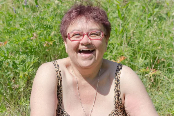 笑う大人の女性は明るい夏の太陽の下で草の中で日光浴 — ストック写真