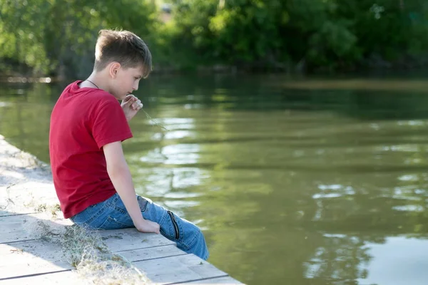 Zamyślony Chłopiec Siedzi Drewnianym Molo Obniżona Nogi Wodzie Jest Gryząc — Zdjęcie stockowe