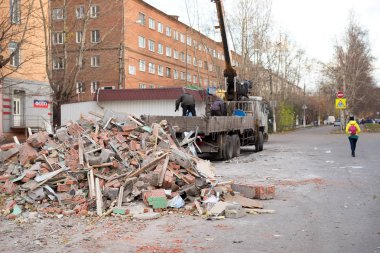 Krasnoyarsk, Krasnoyarsk Bölgesi /Rf-Ekim 29,2018: işçiler kamu hizmetlerinin bir kamyon sokakta apartment building yakınındaki eski ahırda yıkılması üzerinden inşaat atıkları koymak