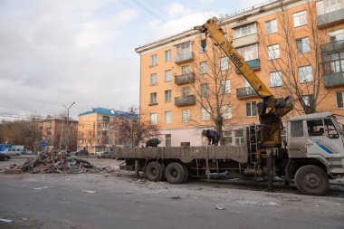 Krasnoyarsk, Krasnoyarsk Bölgesi / Rf - 29 Ekim 2018: kamu hizmeti çalışanları koymak inşaat kirli bir kamyonetteki eski pavyonlar yıkım üzerinden bir vinç ile sonbahar bir şehir sokak.