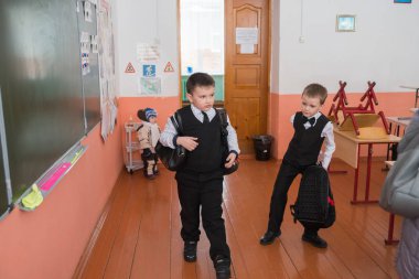 Belogorsk, Kemerovo bölgesi / Rf - 22 Mart 2018: sırt çantaları ile birinci sınıf öğrencileri Belediye kırsal İlköğretim Okulu derslerde sonra kapıyı karşı okul yönetimi yakınındaki standı.