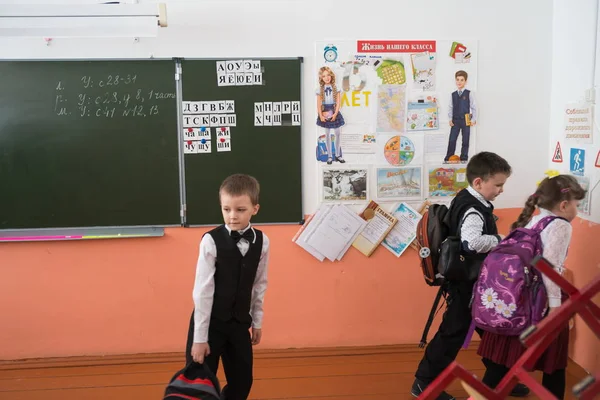 Belogorsk, Kemerovo bölgesi / Rf - 22 Mart 2018: bir birinci sınıf öğrencisi bir sırt çantası ile eve gitmek ve okul yönetim kurulu önünde duruyor ve sınıf sınıf dersten sonra gidiyor.