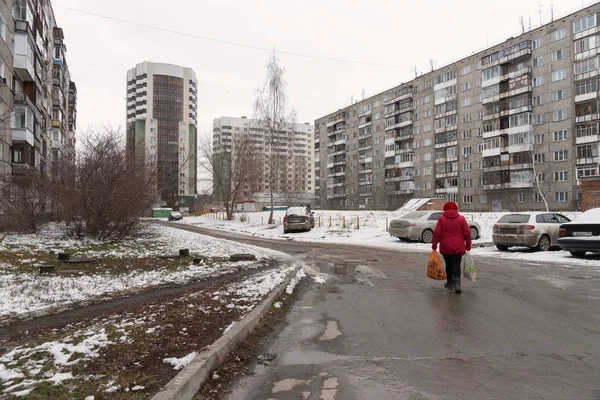 Женщина Красной Одежде Идет Дороге Между Многоквартирными Домами Припаркованными Автомобилями — стоковое фото