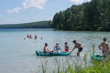 Ingol Lake, Sharypovo District, Krasnoyarsk bölgesi / Rf - 6 Temmuz 2014: şişme bir teknede orman arka planı Ingol göl kenarında rahatlarken için kayan nokta kişi toplandı.