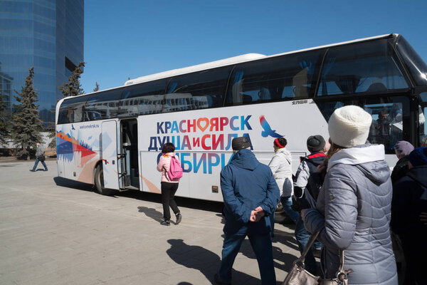 Красноярск, Красноярский край / РФ - 5 апреля 2019 года: Группа туристов спешит к двухэтажному туристическому автобусу с надписью "Красноярск - душа и сила Сибири" на городской площади
.