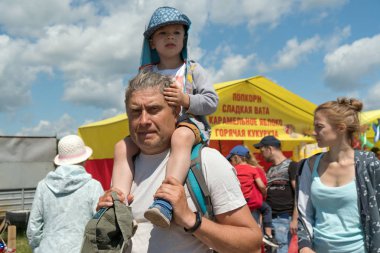 Parnaia, Sharypovskiy bölgesi, Krasnoyarsk bölgesi/ Rf - 5 Temmuz 2019: Büyük bir gölün kıyısındaki karatag etnik festivali sırasında dedesi torunu omuzlarında.