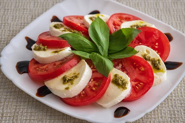 Assiette de salade de caprese classique sain avec tomates et fromage mozzarella avec des feuilles de basilic frais sur une nappe en lin léger. Concept de cuisine italienne — Photo