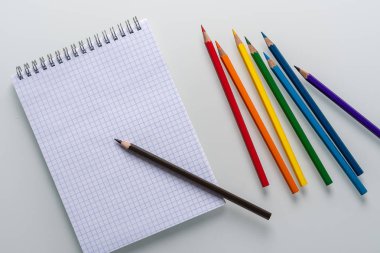 Üzerinde kalem ve beyaz arka plan üst görünüm kopya alanı gökkuşağı renkli kalemler ile bir kafes içinde temiz not defteri