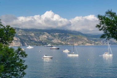 Ufuk dağlarında yüzen yatlar, bulutlarla mavi gökyüzü olan körfez. Fransız Rivierası