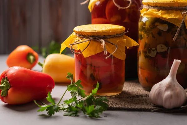 Bocaux faits maison de poivrons et tomates marinés sur un fond de bois rustique. Produit mariné et en conserve. Prochain ingrédients pour la cuisine . — Photo