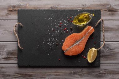 Çiğ somon bifteği. Karanlık bir tahtada. Bir yağ ve limon zeytinyağı. Sağlıklı yiyecekler. Üstte görüntü