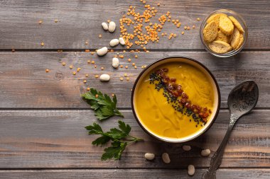 Ahşap bir arka plan üzerinde fasulye ve baharat karışımı ile Krem çorba. bir kaşık ve kraker bir kase yanında