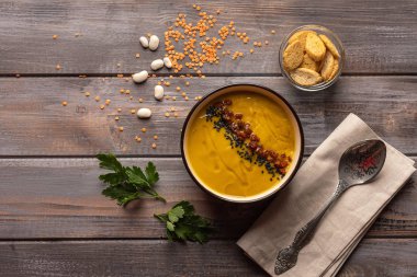 Ahşap bir arka plan üzerinde fasulye ve baharat karışımı ile Krem çorba. bir peçete ve kraker bir kase bir kaşık yanında