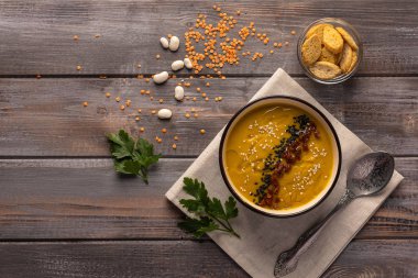 Tahta bir masada peçete üzerinde fasulye ve baharat ile Kremalı çorba. Maydanoz yaprakları ile kraker ve fasulye bir kase yanında