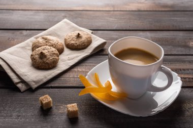 Şekerlenmiş portakal ve şeker topakları ile siyah kahve fincan. Keten peçete üzerine kurabiye