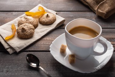 Bir kaşık ve şeker topakları ile siyah kahve fincan. Yanında keten peçete ve bir çanta üzerinde bisküvi var.