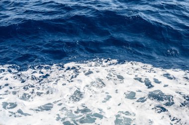 Küçük dalgalar ve beyaz köpük ile arka plan mavi deniz