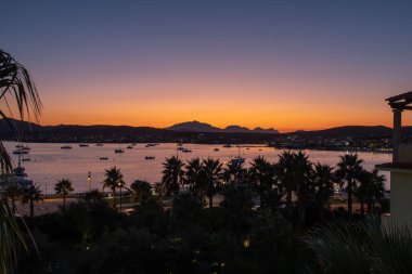 Panoramic view of the orange sunset on the background of the mountains and the sea with a purple tint of the sky