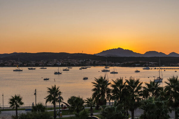 Close-up of sunset against mountains and sea with yachts