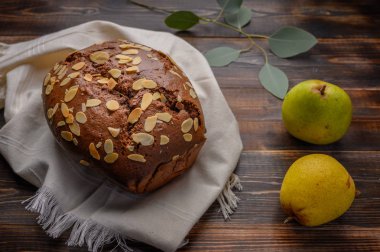 Masadaki keten peçetede zencefil ve kakule ile ev yapımı çikolatalı armut keki. Armut ve dalların yanında yapraklar