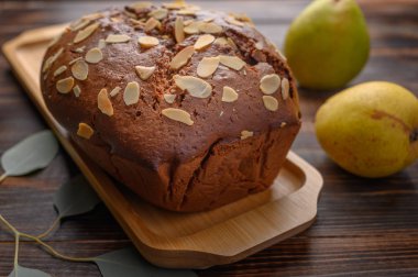 Yakın plan seçmeli ev yapımı çikolatalı armutlu kek, zencefil ve kakule ile ahşap tepside. Armutların ve yapraklı bir dalın yanında.