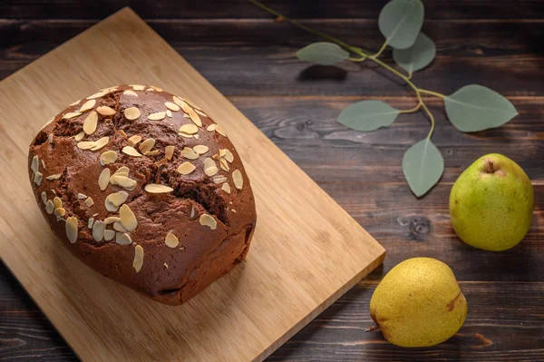Tahtaya zencefil ve kakule sürülmüş ev yapımı çikolatalı armut keki. Armut ve dalların yanında yapraklar