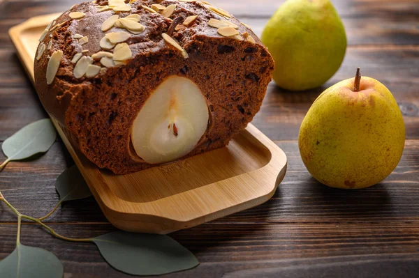 Tahta tepside zencefilli kakule ve kakule ile ev yapımı dilimlenmiş çikolatalı kek. Yarım armut kesilmiş.