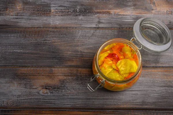 Hojas de col en escabeche caseras y pimienta y zanahorias en un frasco de vidrio con una tapa abierta sobre un fondo marrón de madera. Estilo rústico —  Fotos de Stock